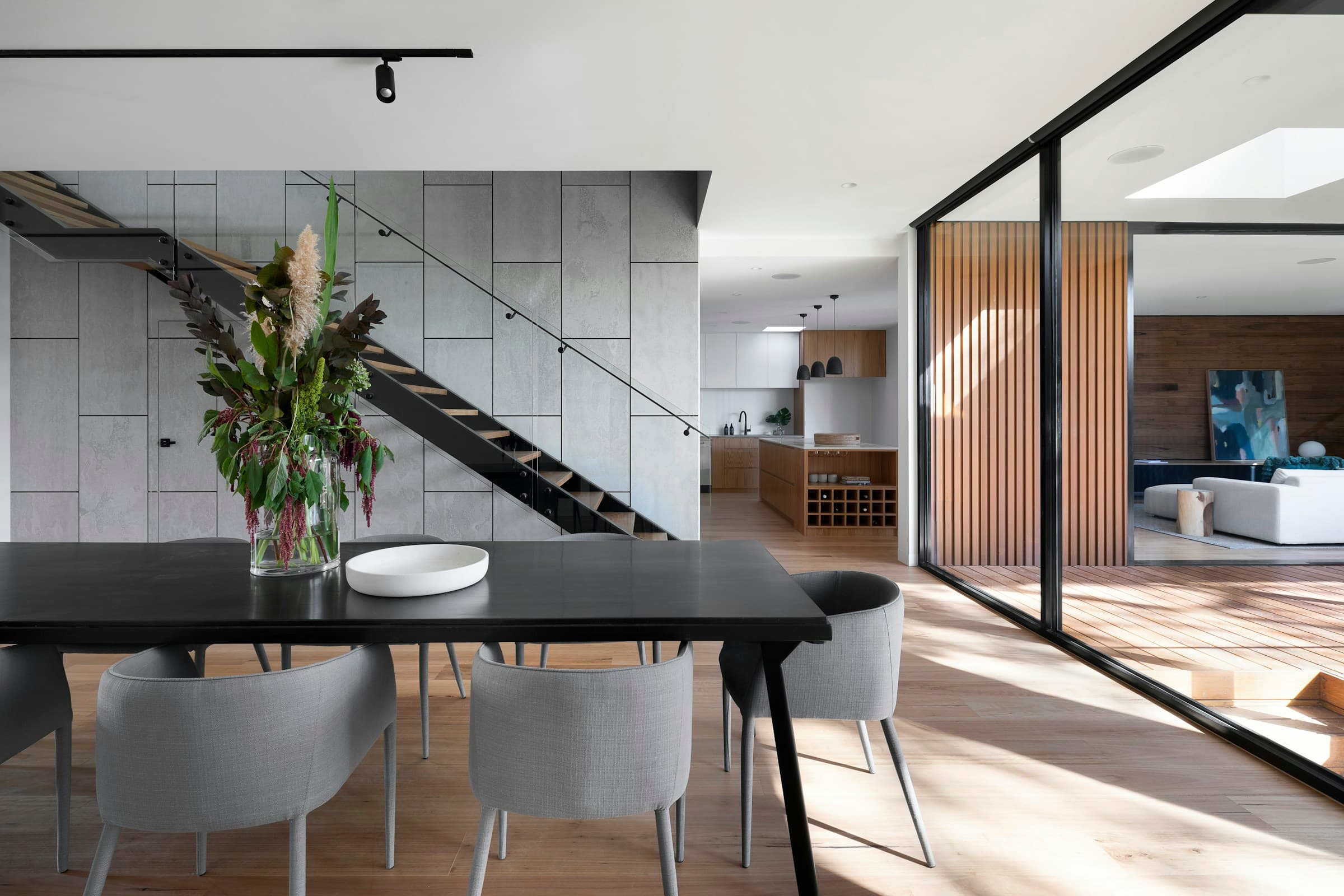 Interior abierto con escalera de líneas limpias, madera y grandes ventanales